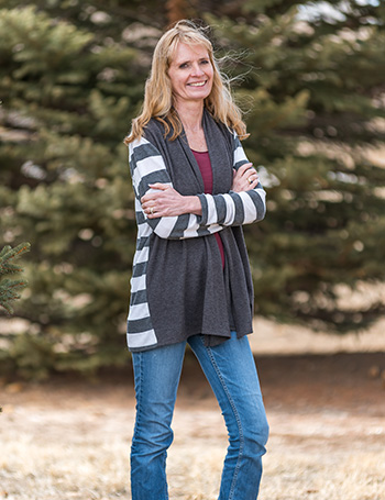 about-annette standing and smiling outside by tree
