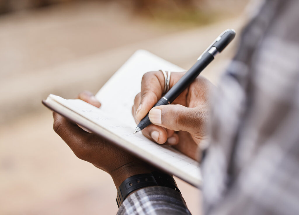 Cropped shot of someone writing in a notebook journal.